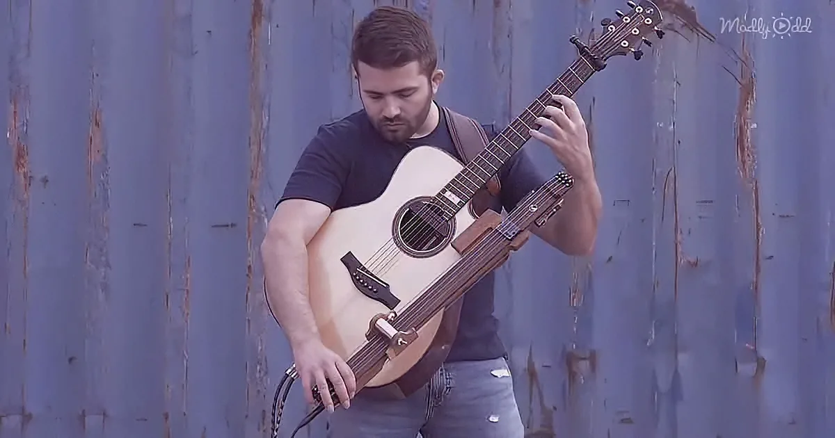 A man plays a unique guitar with multiple necks against a rustic blue wall.