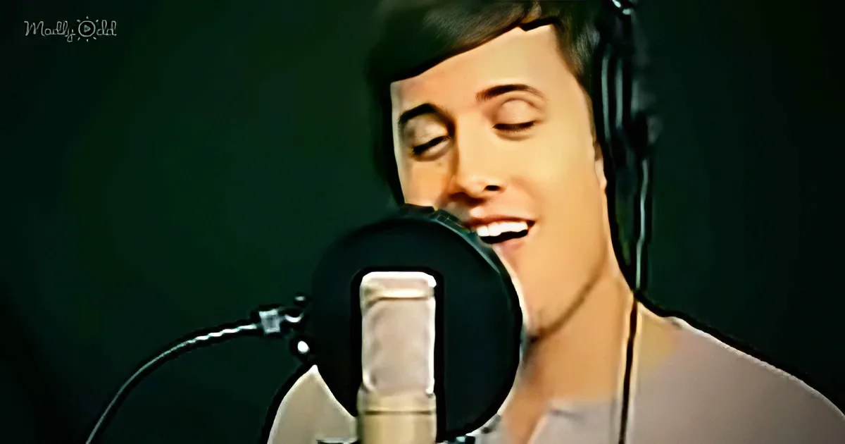 A man wearing headphones sings into a microphone in a recording studio setting.