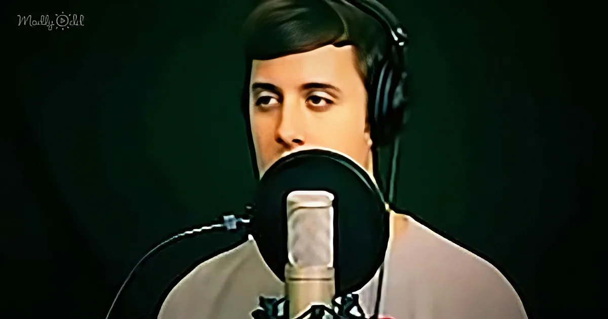 A person wearing headphones stands in front of a microphone, likely recording or broadcasting.