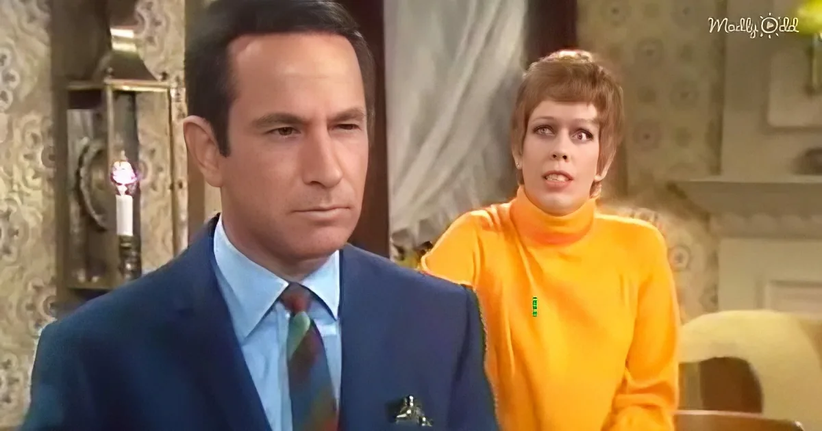 A man in a blue suit and tie stands in front of a woman in an orange turtleneck, both in a vintage setting.