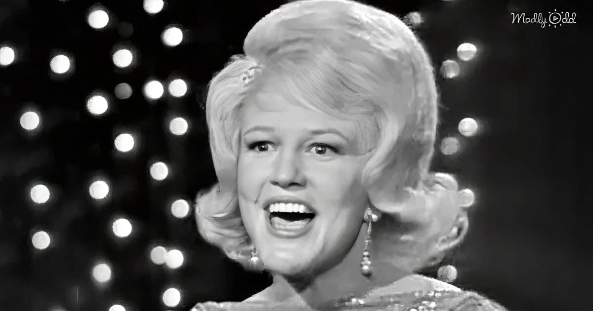 A woman with blonde hair styled in a 1960s fashion, wearing earrings, and smiling with a black-and-white background of...