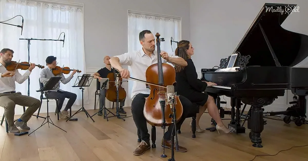A man plays cello in a small ensemble with violinists, a cellist, and a pianist in a studio setting.