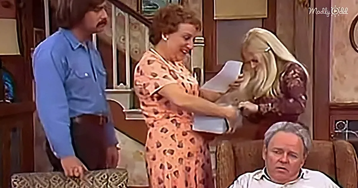 Woman in floral dress hands document to blonde woman while man in blue shirt watches.