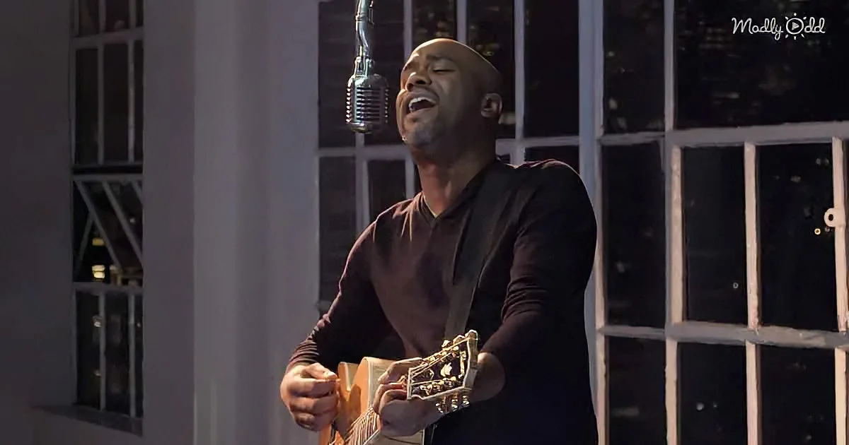 A man sings passionately while holding a guitar, standing in front of a microphone.
