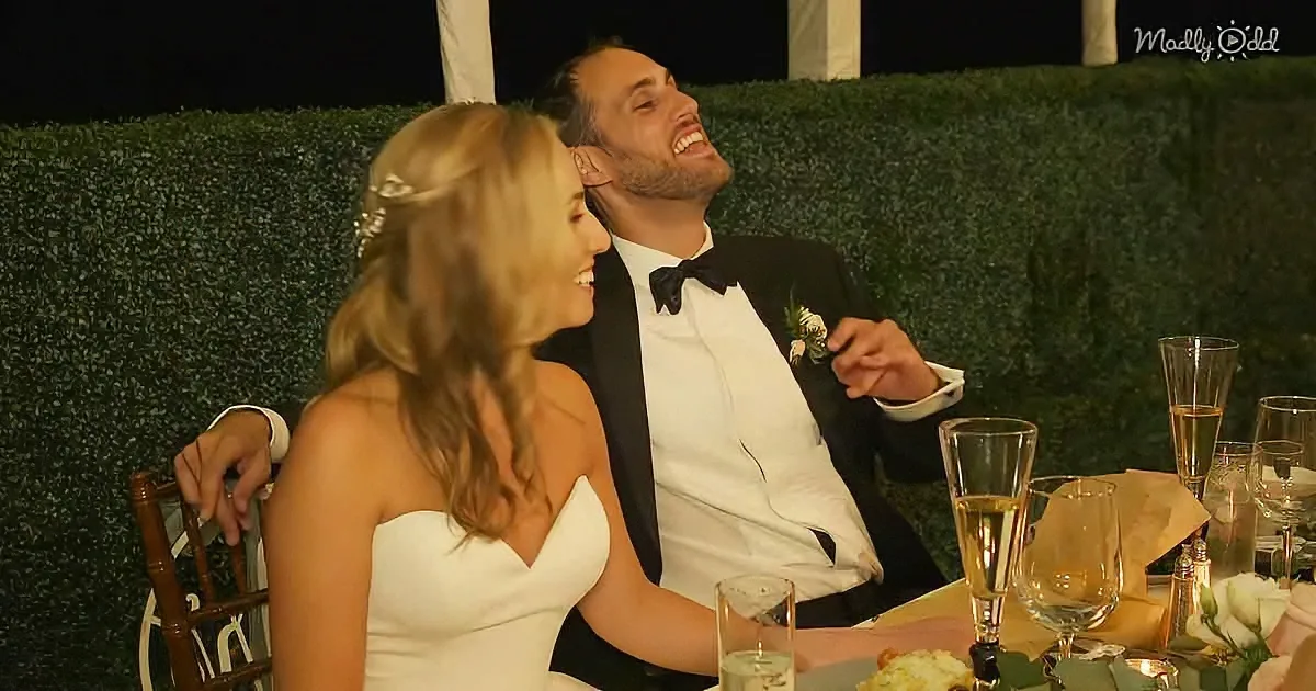 A bride and groom share a joyful moment at their wedding reception, surrounded by champagne glasses and floral decorations.