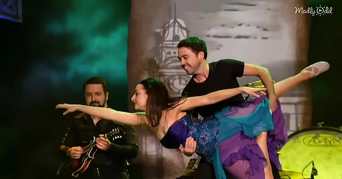 A man and woman perform a dance with a musician playing a string instrument in the background.