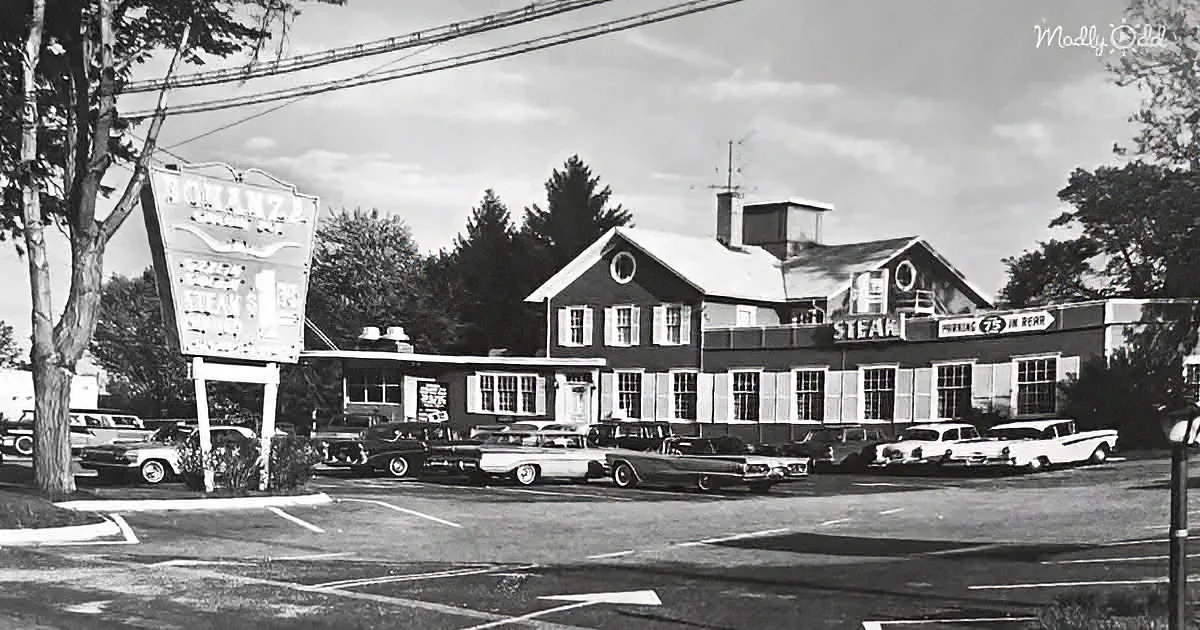 A vintage diner with classic cars parked in front, sign reading "Steaks" and "Pizza."