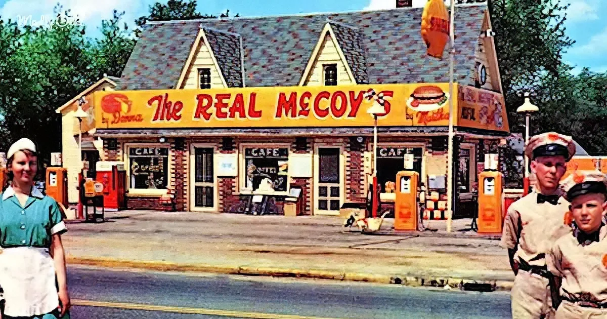 The Real McCoy's cafe, a vintage roadside establishment with gas pumps and a sign featuring a burger, stands prominently...