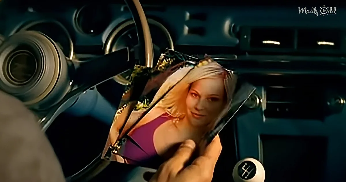 A person holds a photograph of a woman with blonde hair in a car interior.