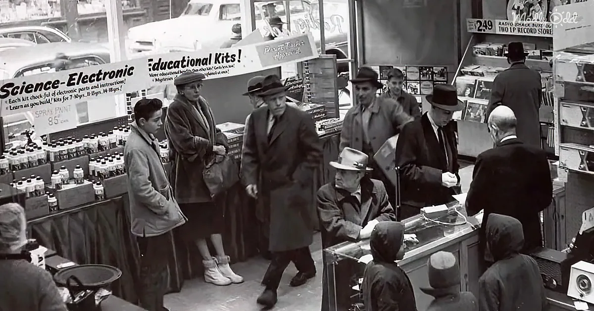 People shopping in a store with educational kits and vintage cars visible outside.