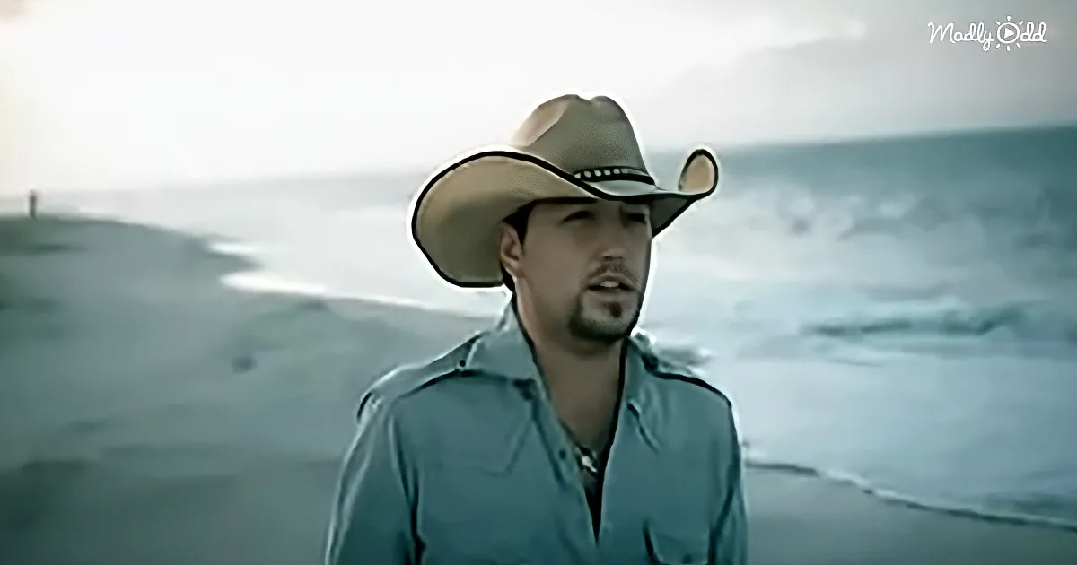 A man in a cowboy hat and light blue shirt stands against a blurred, snowy landscape.