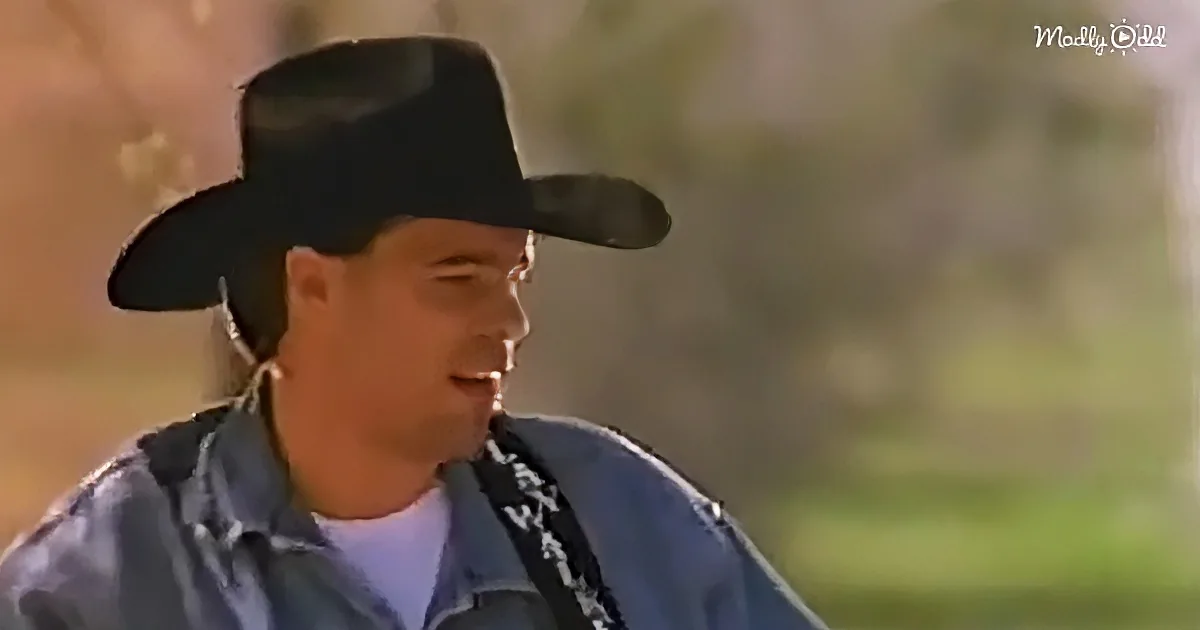 A man wearing a black cowboy hat and a blue shirt is seen in a close-up shot.