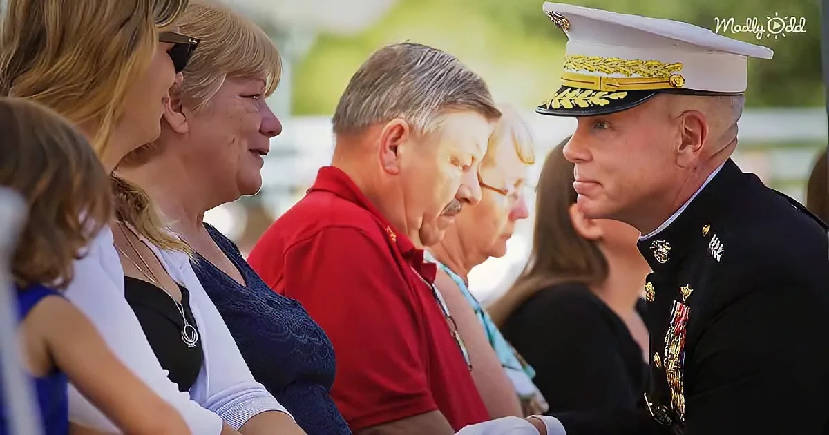 A Marine in uniform speaks to a woman in a crowd at what appears to be a formal event.
