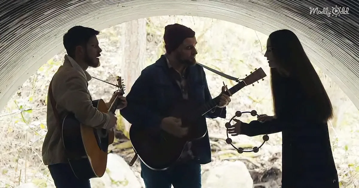 Three musicians play inside a tunnel, one with guitar, another with tambourine, and the third with a stringed instrument.