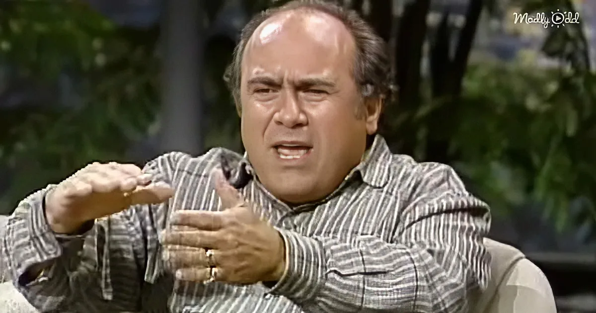 A man in a striped shirt gestures dramatically with his hands, appearing to speak passionately.
