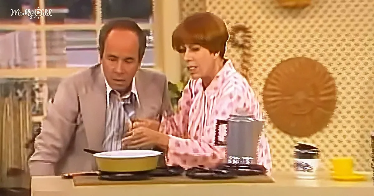 A man and woman are seated at a table, engaged in conversation, with a bowl and utensils in front of them.