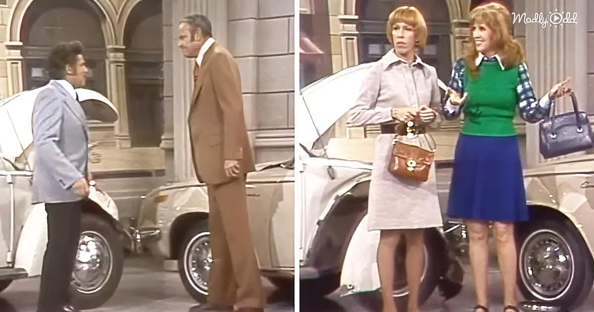 A man in a brown suit stands beside a white car, while two women in vintage attire stand nearby, holding purses.