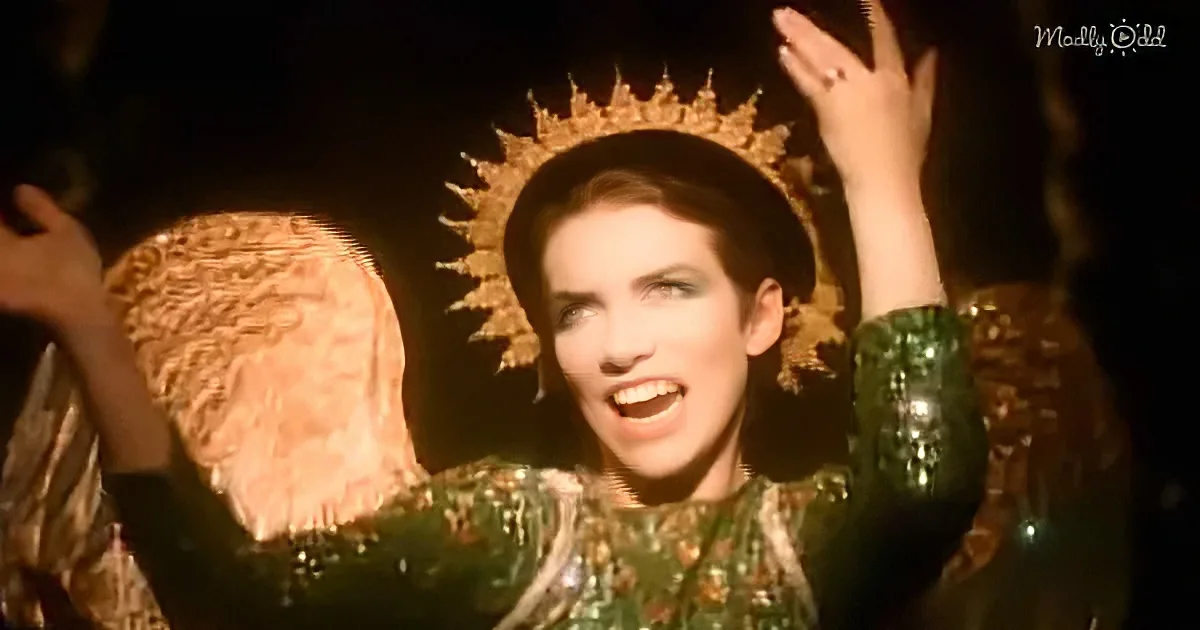 A person in a green, ornate outfit and crown raises their hands, possibly in a performance or ritual.