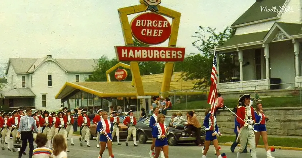 A Burger Chef sign with a marching band in red and white uniforms in front of it.