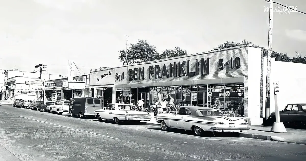 A vintage Ben Franklin 5-10 store with classic cars parked in front, set against a backdrop of other small businesses.