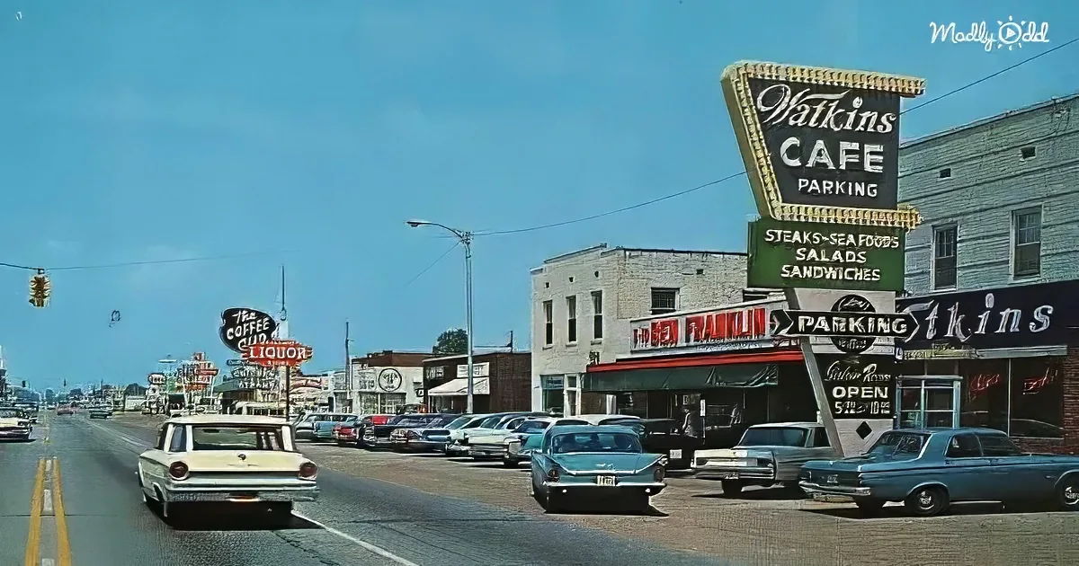 Watkins Cafe sign stands out with retro cars and classic storefronts lining the street.