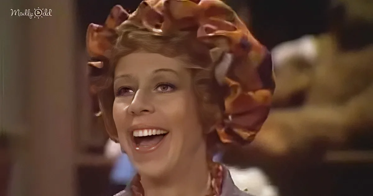 A smiling woman with a large, colorful hair accessory on her head.