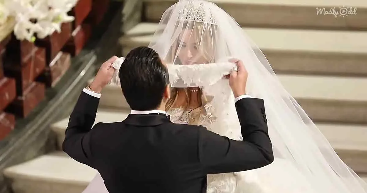 A groom adjusts a bride's veil during a wedding ceremony.
