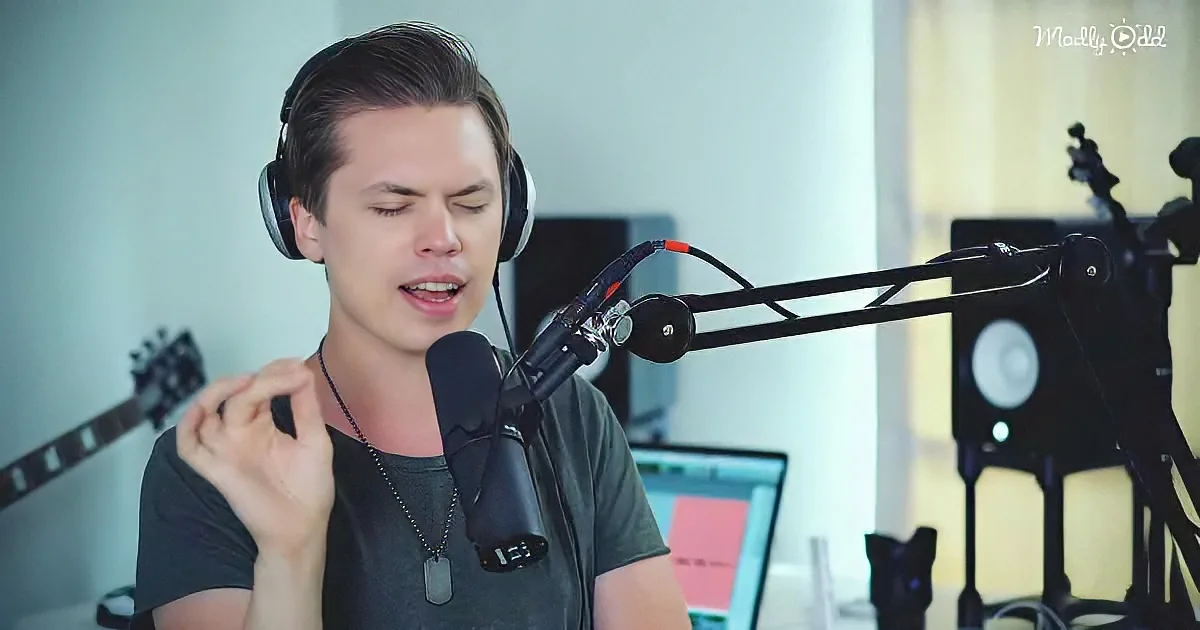A person wearing headphones sings into a microphone in a recording setup.