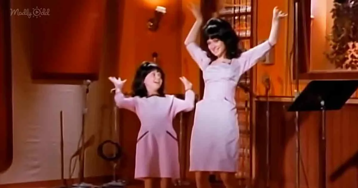 A woman and a child in matching pink dresses raise their arms in a joyful pose on stage.
