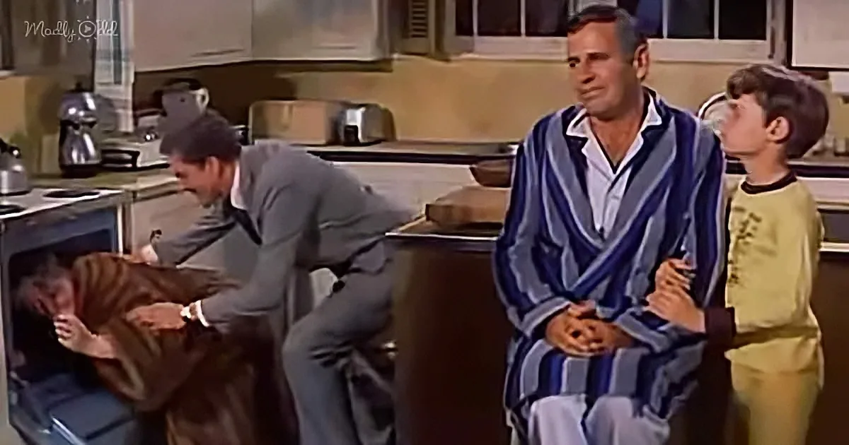 A man in a striped robe holds a child while another man in a suit tries to remove a cat from an oven.