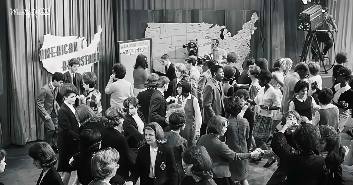 A large group of people, possibly contestants, gather around a map of the United States in a studio setting.