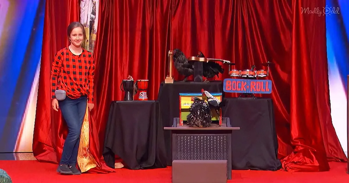 A woman in a red plaid shirt stands beside a stage setup with roosters and a sign reading "Rock 'n' Roll."