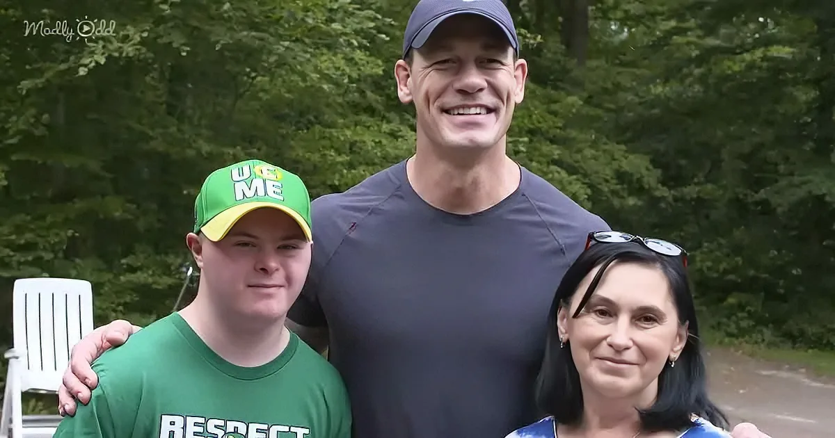 A man in a blue cap and gray shirt poses with two others, one in a green shirt and the other in a blue shirt, in a park...