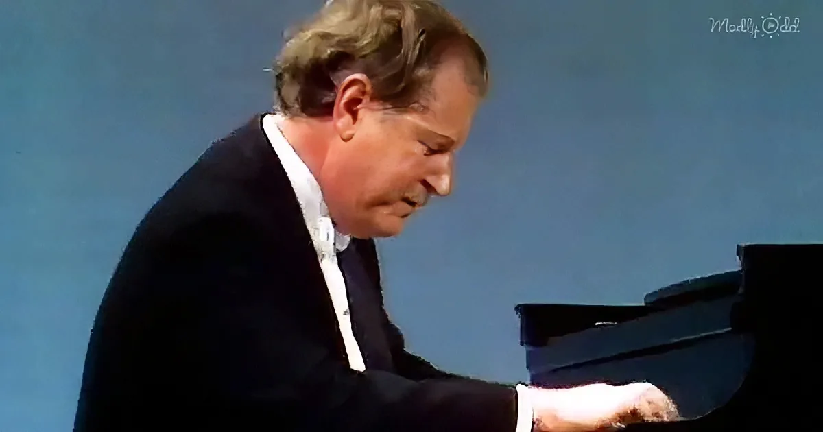 A man in a suit plays a grand piano against a clear blue sky.