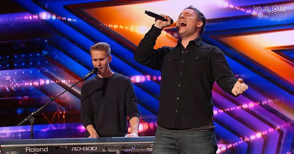 A man in black shirt sings passionately on stage with another playing keyboard.