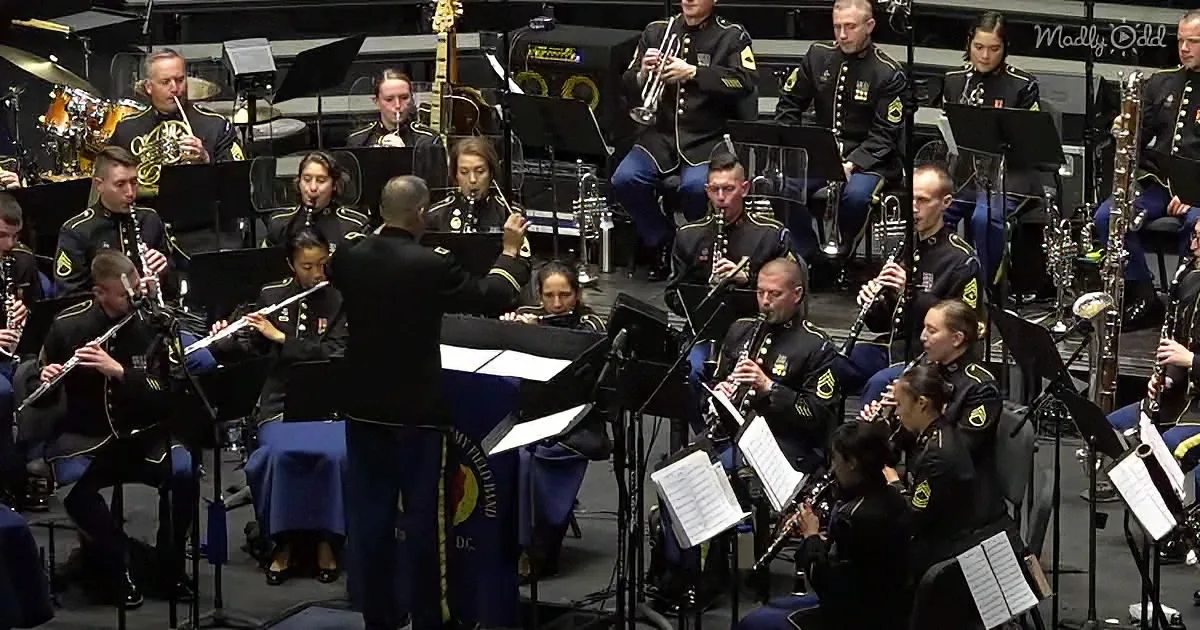 A military band in uniform plays instruments under a conductor's direction.