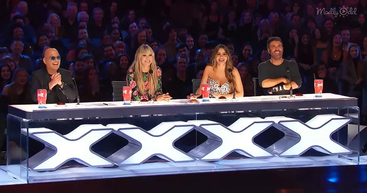 Four judges sit at a table with "XXXX" in front, facing a large audience.