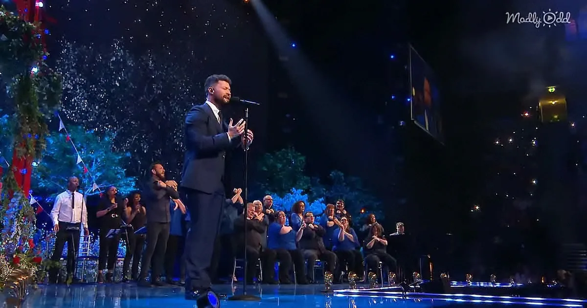 A man in a suit sings on stage, surrounded by a choir and festive decorations.