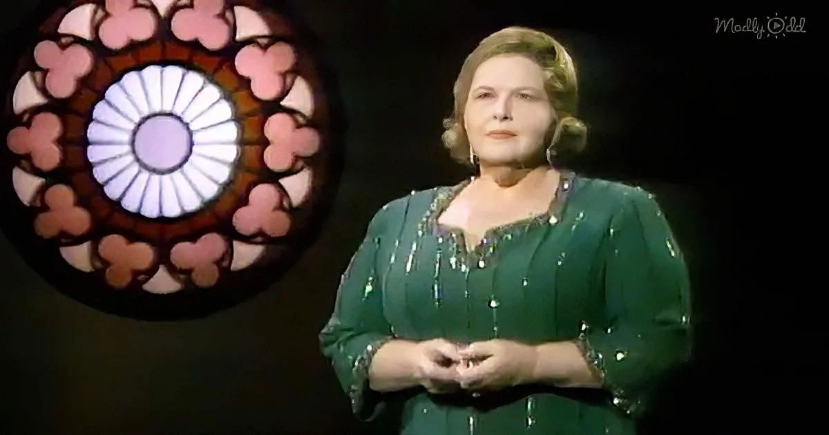 A woman in a green sequined dress stands in front of a stained glass window.