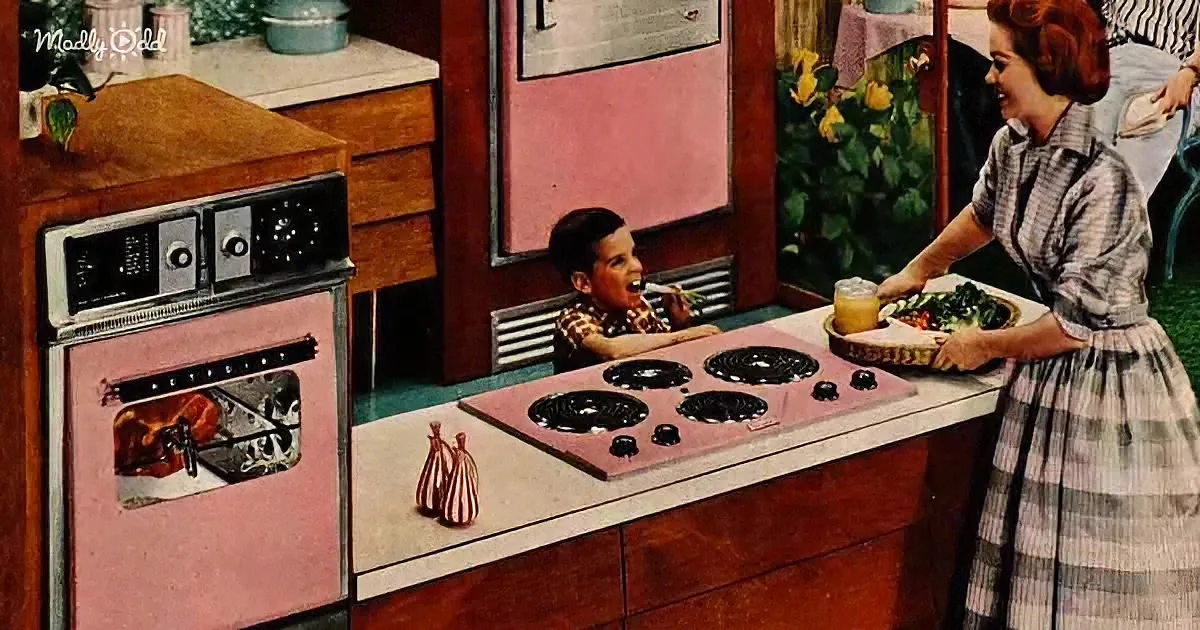 Woman serves salad to boy in retro kitchen with pink appliances and decor.