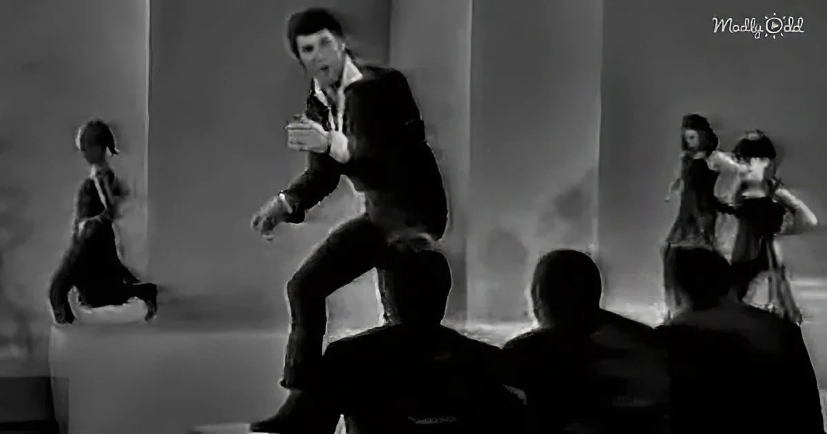 A man in a suit is dancing energetically in front of a group of people.