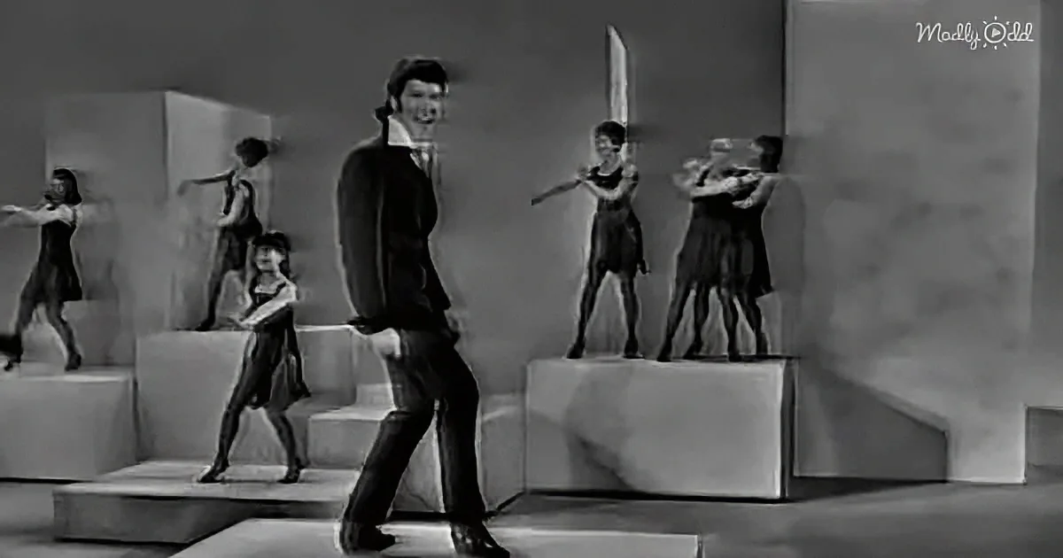 A man in a suit walks past a group of women on pedestals in a surreal, black-and-white scene.