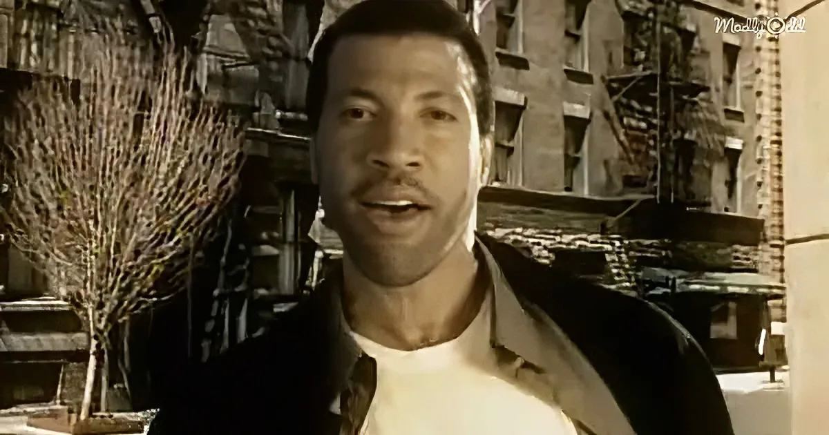 A man in a white shirt and black jacket stands in front of a brick building with fire escapes.