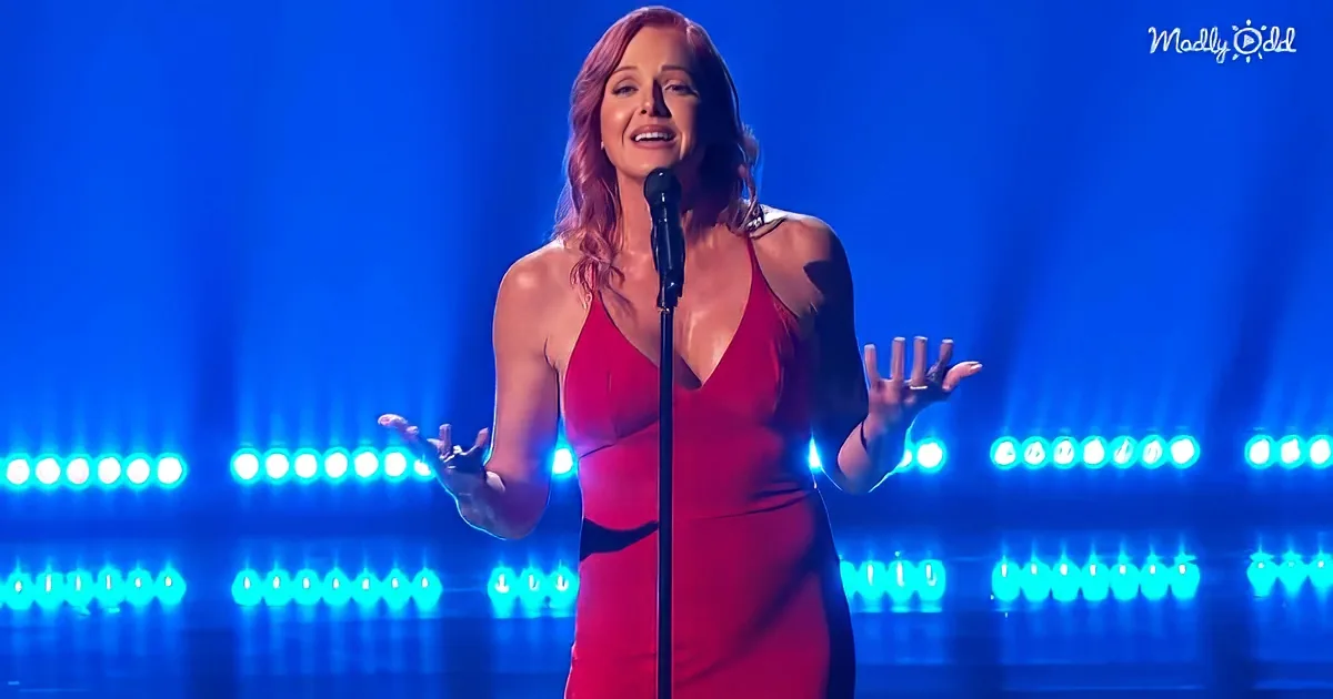 A woman in a red dress sings passionately on stage with blue lights behind her.