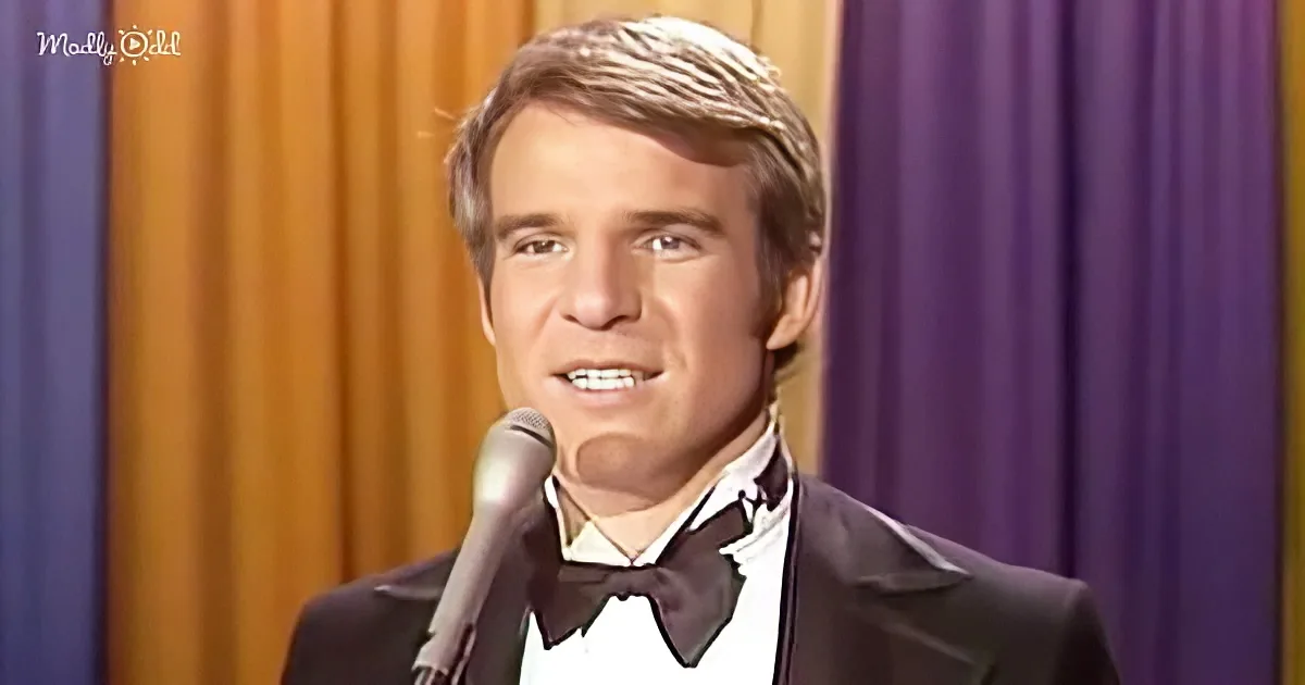 A man in a tuxedo sings into a microphone against a purple and gold curtain backdrop.