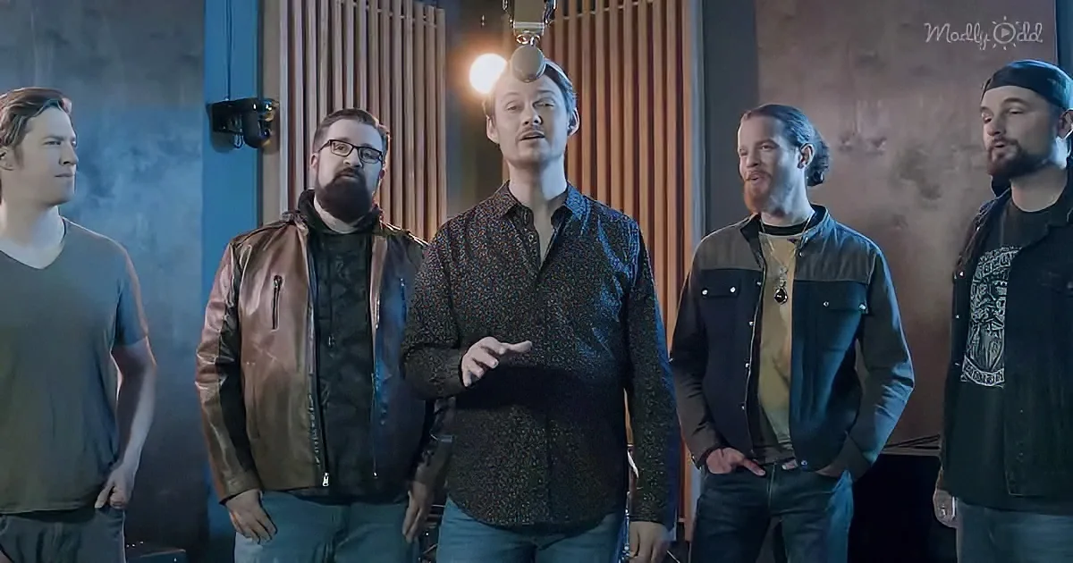 A man in a patterned shirt stands in front of a group of men in a recording studio.