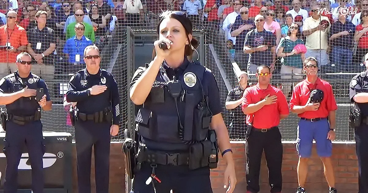 A police officer salutes while standing in front of a crowd during a patriotic event.