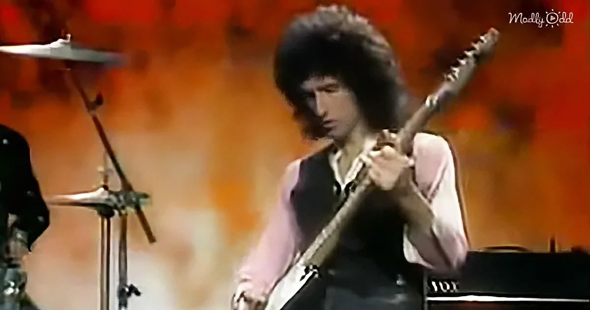 A guitarist with long hair plays an electric guitar on stage, surrounded by musical equipment.