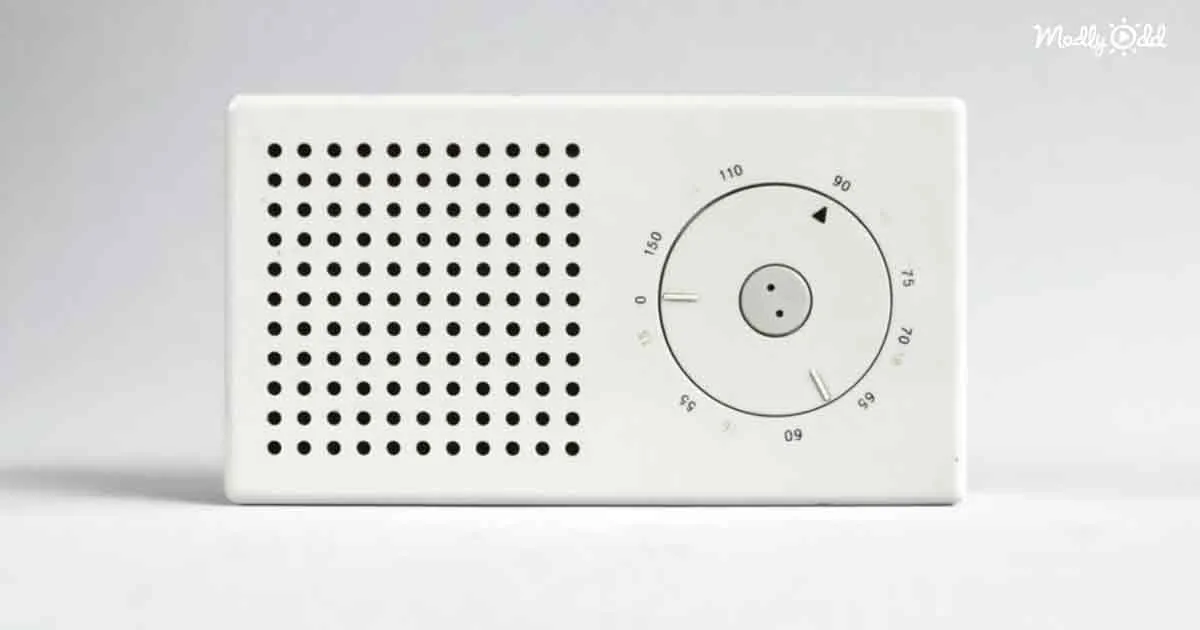 A white rectangular device with a perforated speaker and a circular dial with numbers and a smiley face.