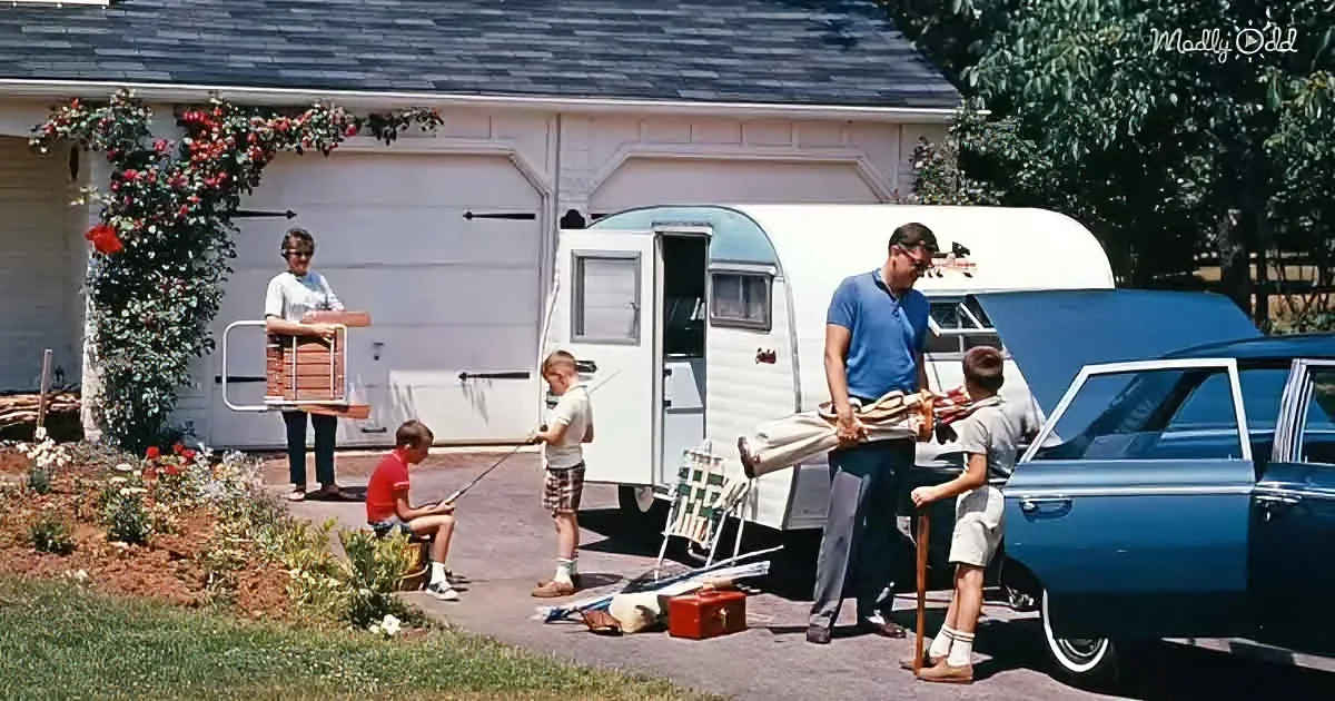 A family prepares for a camping trip in front of their house, with a vintage trailer and classic car.